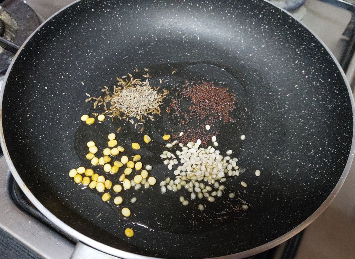 In a pan heat 1-2 tablespoons of oil, splutter 1/2 teaspoon mustard seeds, 1 teaspoon cumin seeds. Add 1/2 tablespoon urad dal and 1/2 tablespoon chana dal, and fry till lentils turn brown and aromatic.