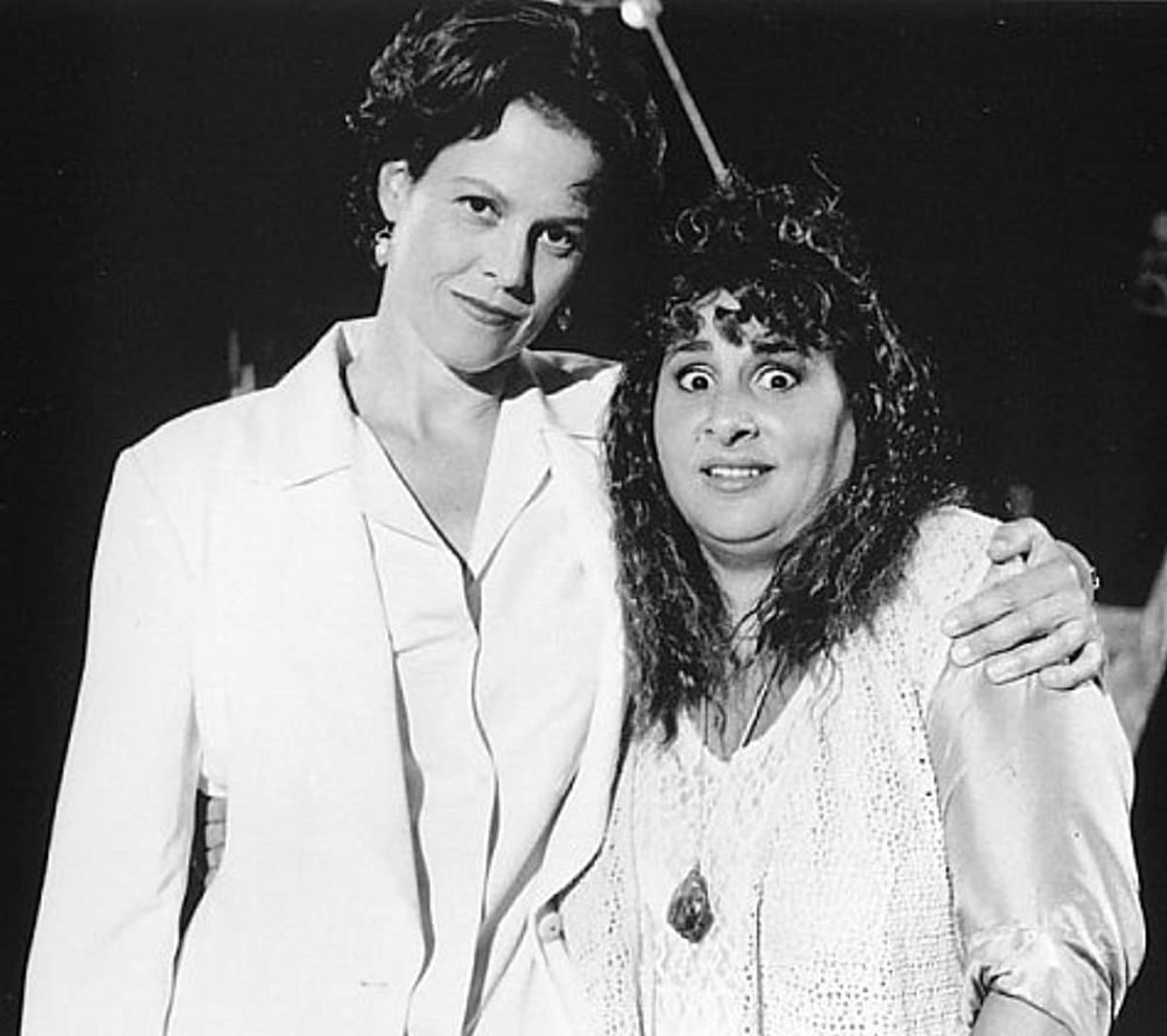 After belittling the audience member with a bad perm, Debra Moorhouse (Sigourney Weaver) poses for an uncomfortable picture
