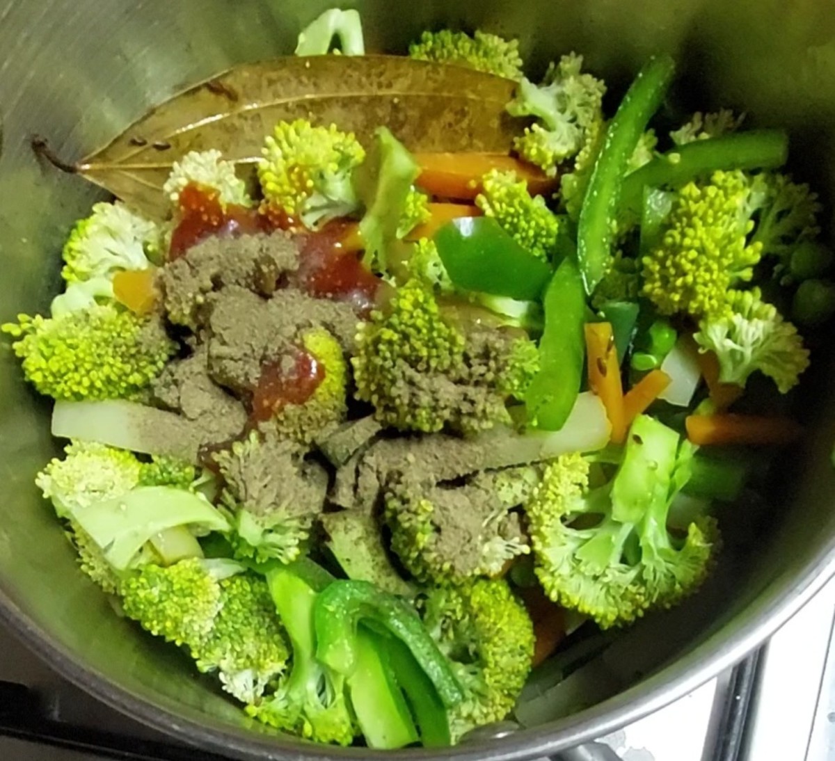 When vegetables are half-cooked (about 10 minutes), open the lid and add capsicum and broccoli. Fry for 1 minute. Add 2 tablespoons tomato sauce, 1 tablespoon green chili sauce and 1 tablespoon pepper powder.