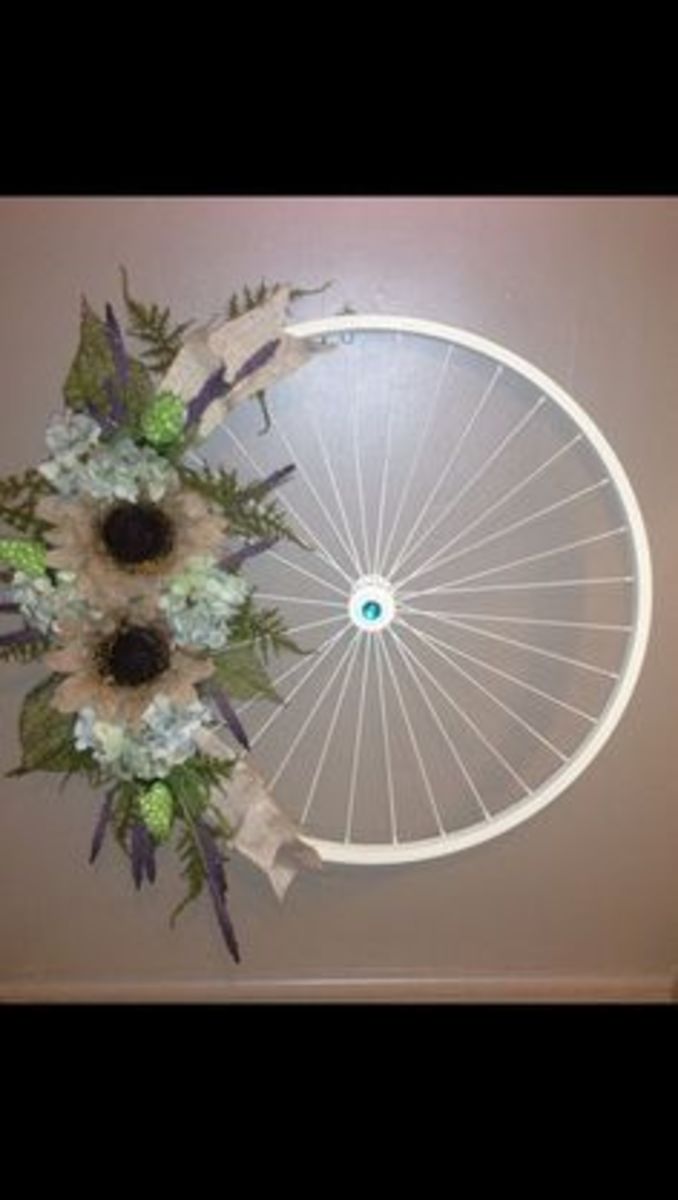 Old bike wheel, spray paint, a glue gun, and 15 bucks worth of flowers!! So simple to make
