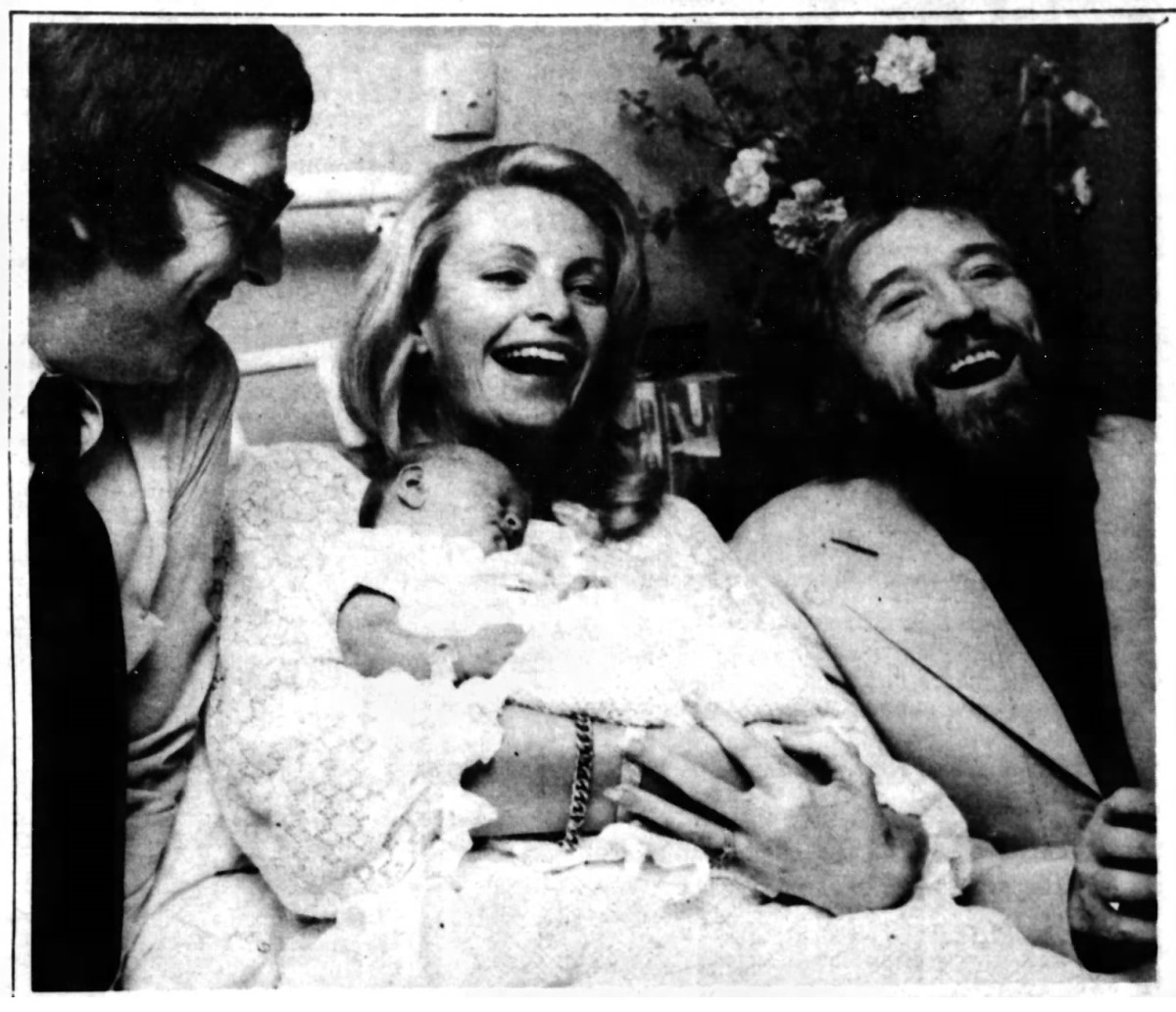 Cassandra, holding her newborn daughter Charlotte, joined by finance Dermot  Harris (left), and Richard Harris (right).