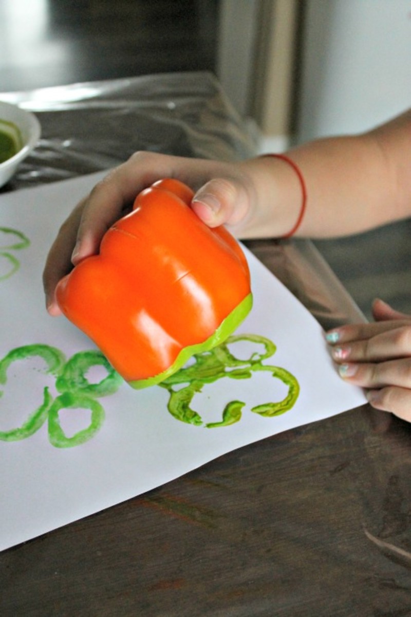 Stamping shamrocks with orange peppers and green paint.