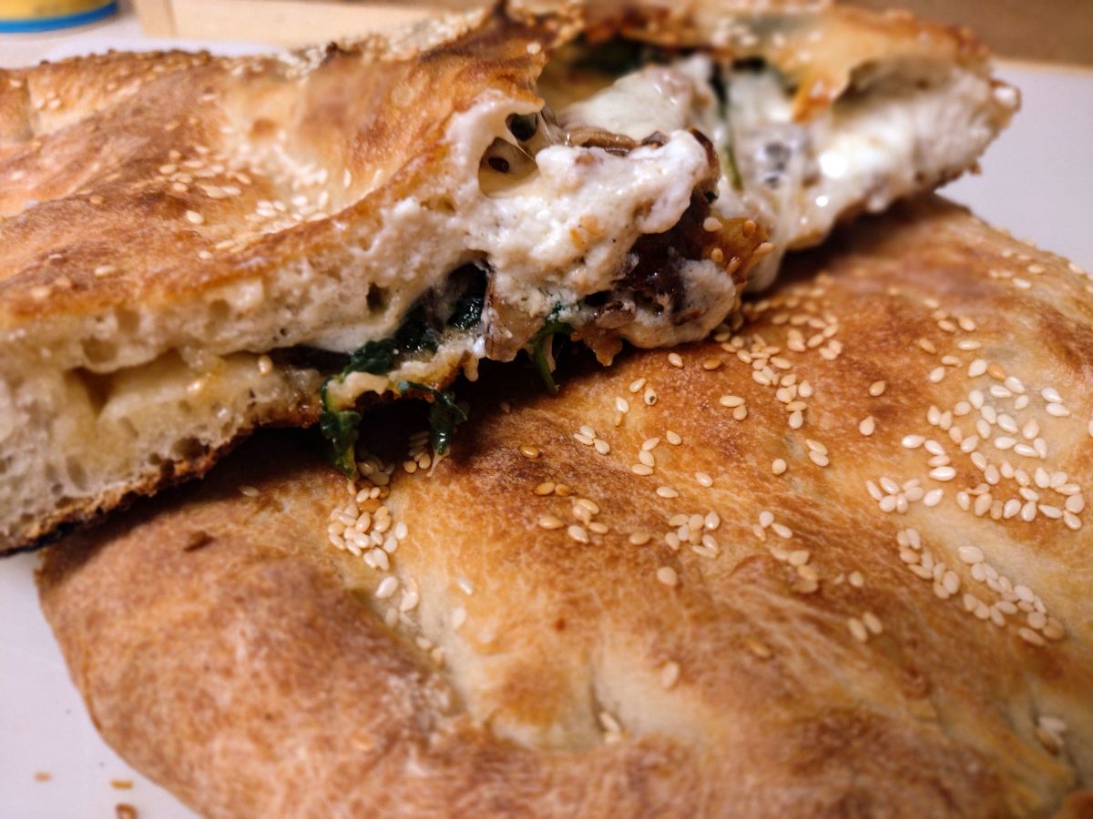 The traditional calzone traces its roots to Naples, Italy, around the early 1700s. This version is topped with sesame seeds.