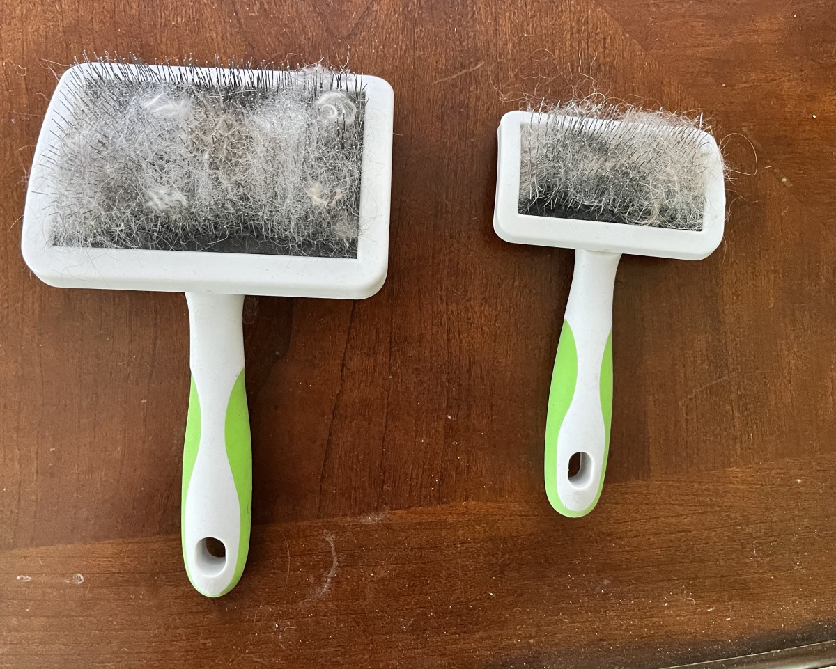 A large and small slicker brush with a white and green handle.