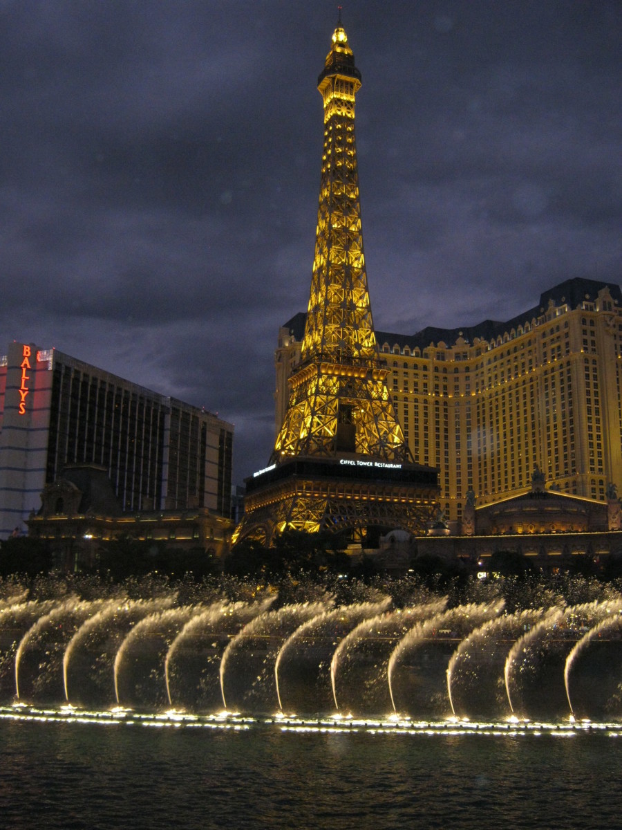 The Fountains of Bellagio with the "Eiffel Tower" (Paris hotel) in the background at dusk.