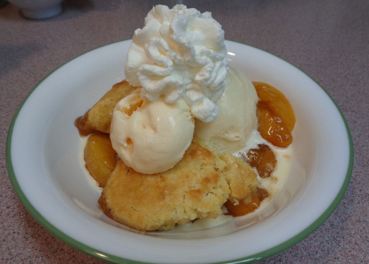 Warm peach cobbler with vanilla ice cream and a touch of homemade whipped cream