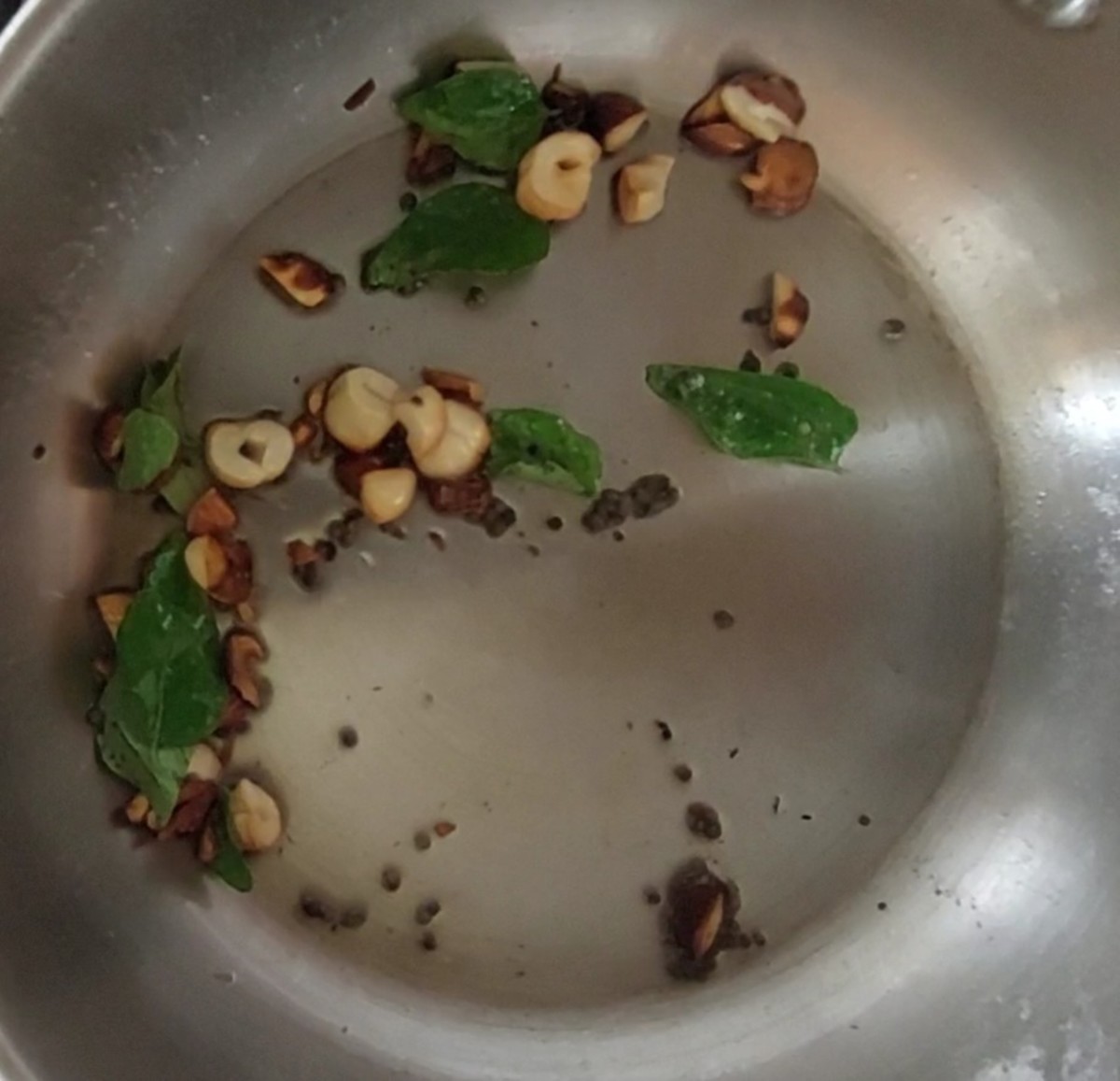 Splutter 1/2 teaspoon mustard seeds. Add 1 teaspoon chopped almonds and 1 teaspoon chopped cashews. Fry till golden brown and crisp. Add 1 sprig curry leaves and fry for a few seconds.