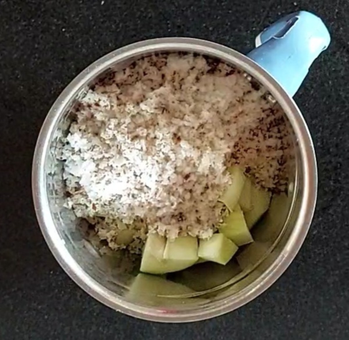 Transfer the cubed raw mango into a mixer jar and add 1 cup grated fresh coconut.
