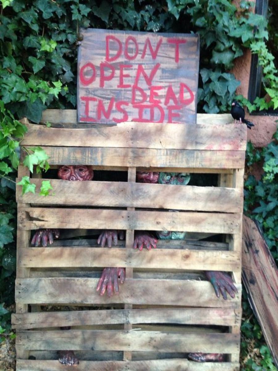 zombie masks, plastic hands and feet from the dollar store to stuff, staple and tape to two wooden pallets. Stacking one pallet in front of the other hides a lot of empty space.