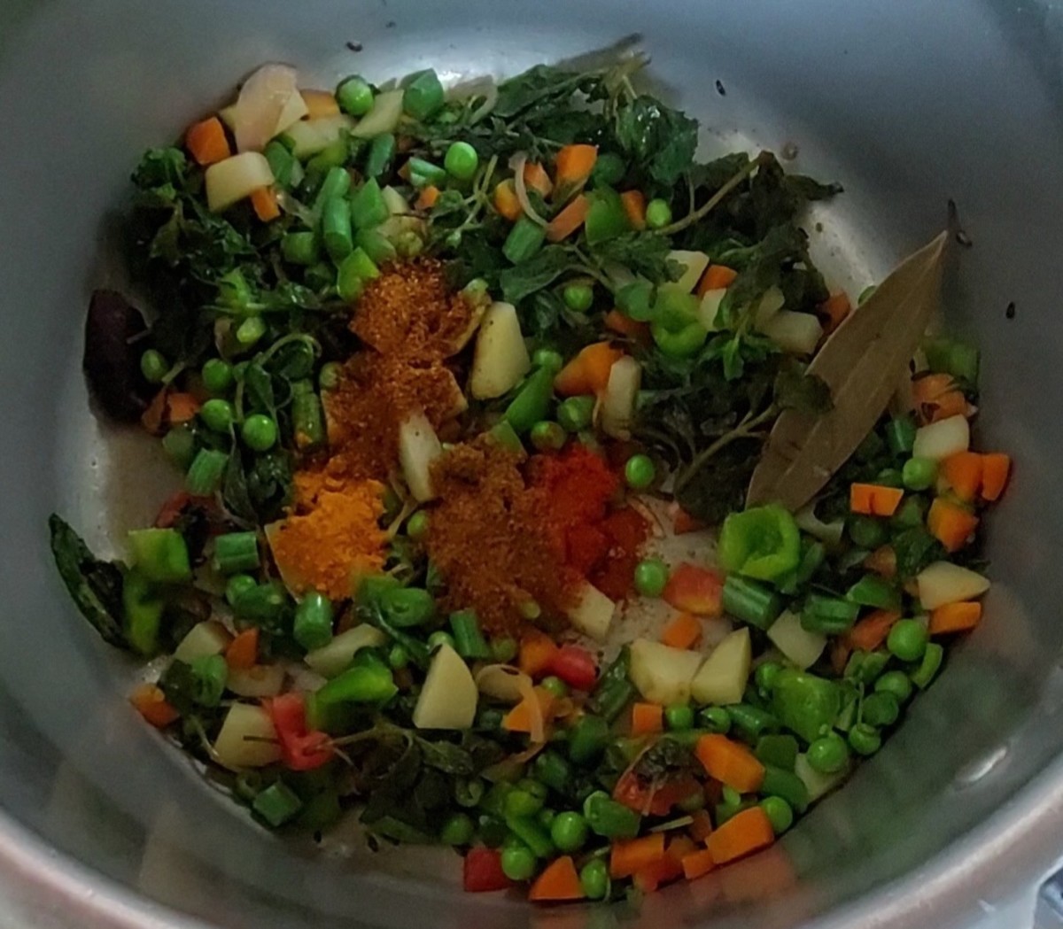 Add 1/2 teaspoon turmeric powder, 1/2 teaspoon red chili powder, 1/2 teaspoon garam masala powder and 1 teaspoon pavbhaji masala powder. Mix to combine spices with vegetables.