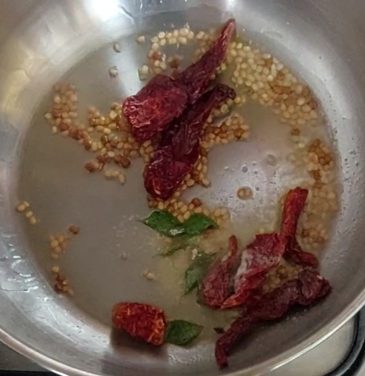 Add 4–5 Byadagi red chilies and saute for a few seconds. Add a sprig of curry leaves and 1/4 teaspoon hing. Fry for a few seconds.