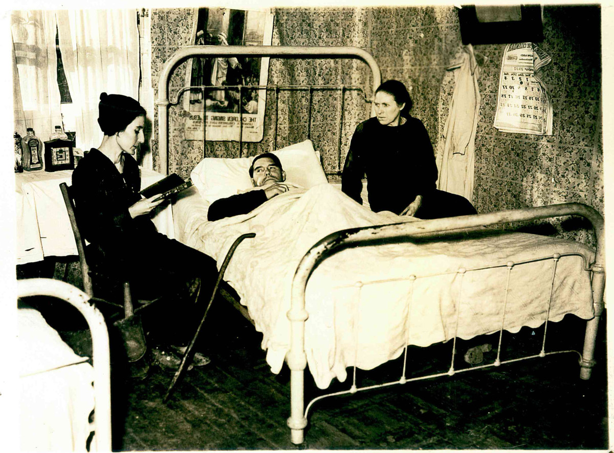 Pack horse librarian reading to a bedridden  man and his wife.