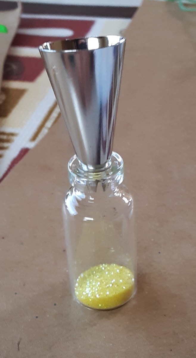 Put glitter into bottle. This is a metal top to squeeze frosting and décor on cakes. It works great as a glitter funnel.