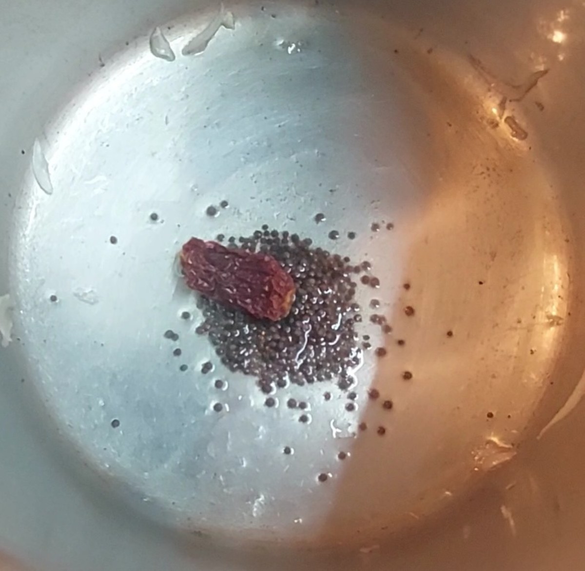 In a cooker, heat 1 tablespoon oil and splutter 1/2 teaspoon mustard seeds. Add 1-2 broken red chilies and fry for a few seconds.