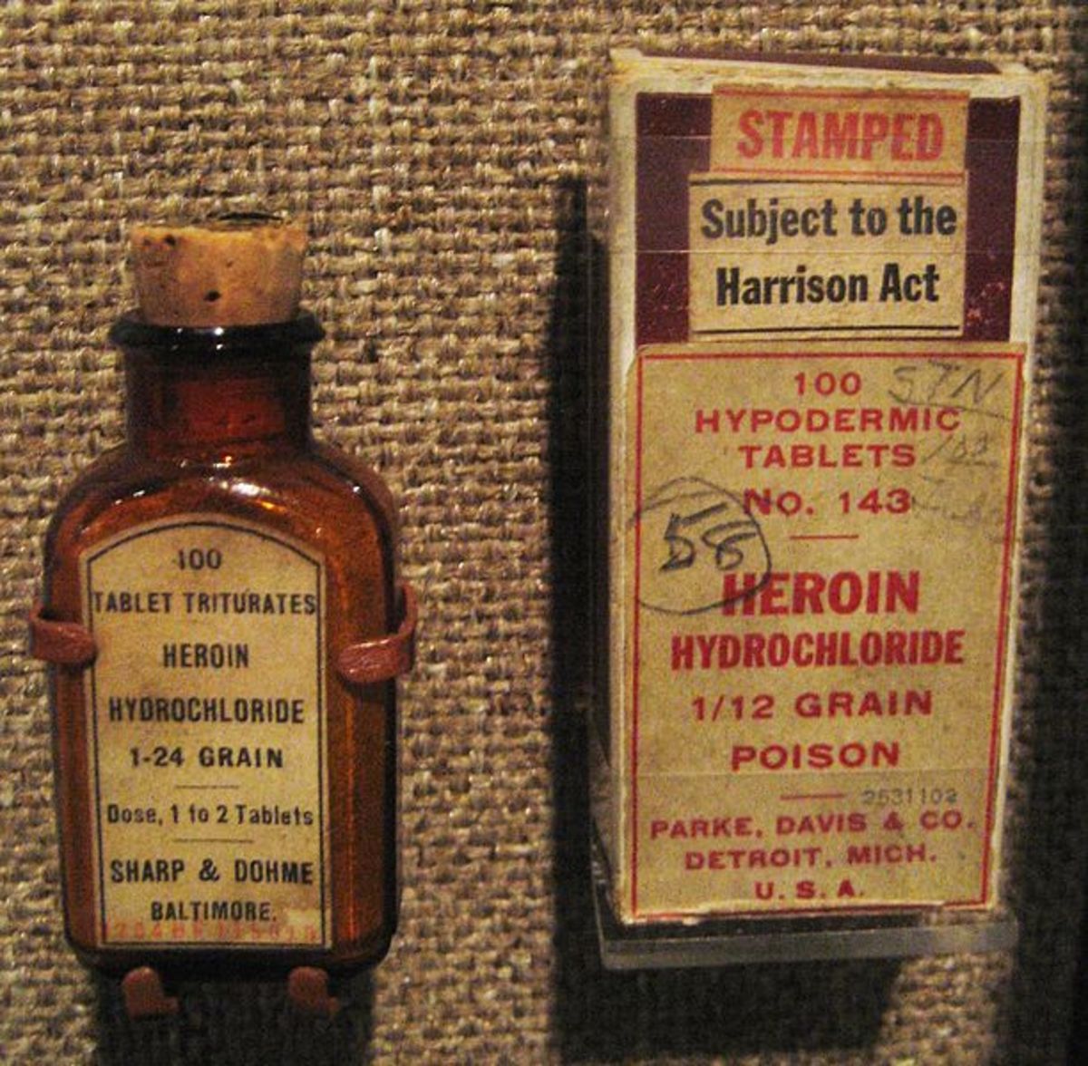 Commercially marketed Heroin containers from the early 20th century. Bottle on left; box on right. The box has a "Harrison Act" tax stamp, indicating a date of 1914 or shortly after. Photographed from display at the Old Mint Museum, New Orleans.