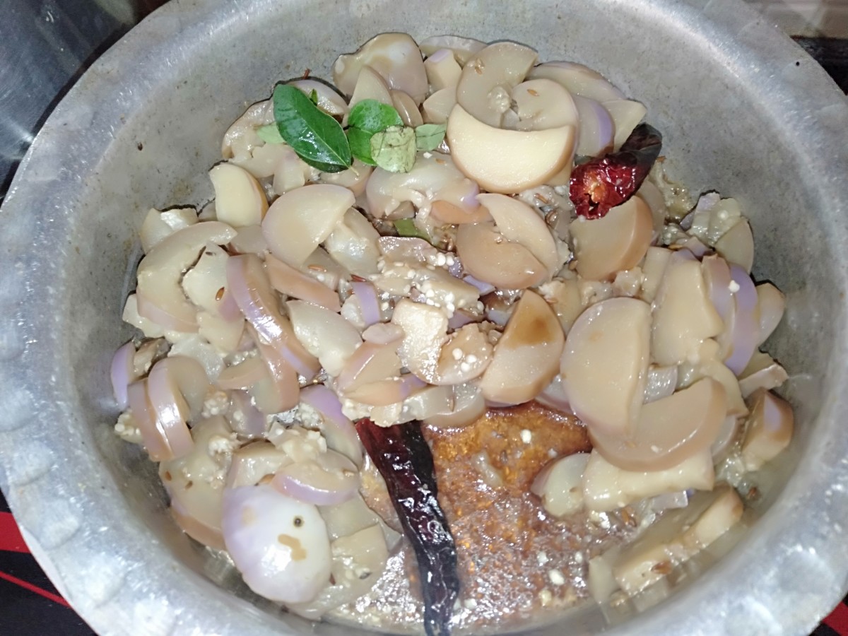 Once the eggplant is cooked well, remove the lid and add curry leaves and tamarind pulp. Mix well.