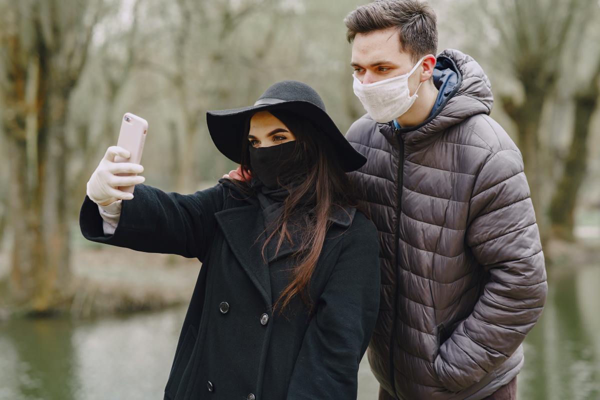 A man and woman taking a picture while wearing masks.