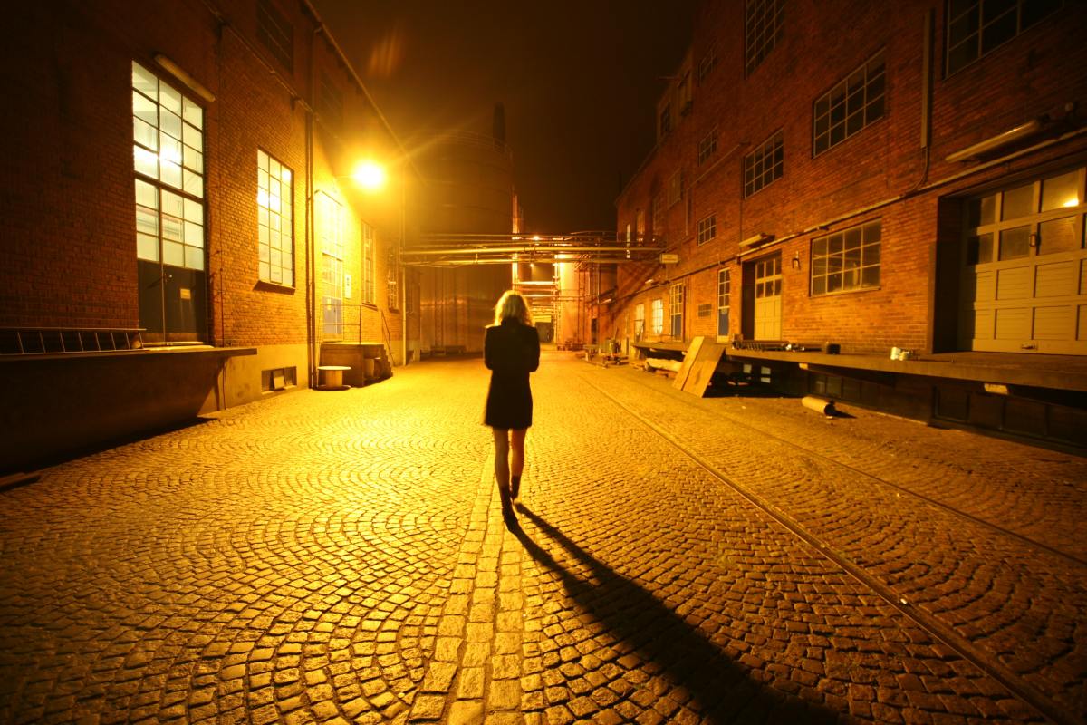 A woman walks alone in a street at night.