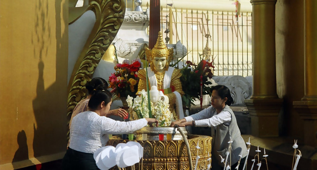缅甸仰光，妇女们在一个祭坛前献上祭品。＂decoding=