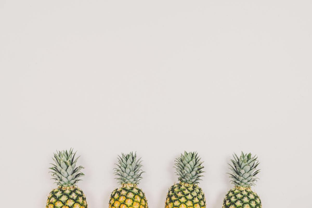 Four pineapples behind a light background. Pineapples does contain manganese.