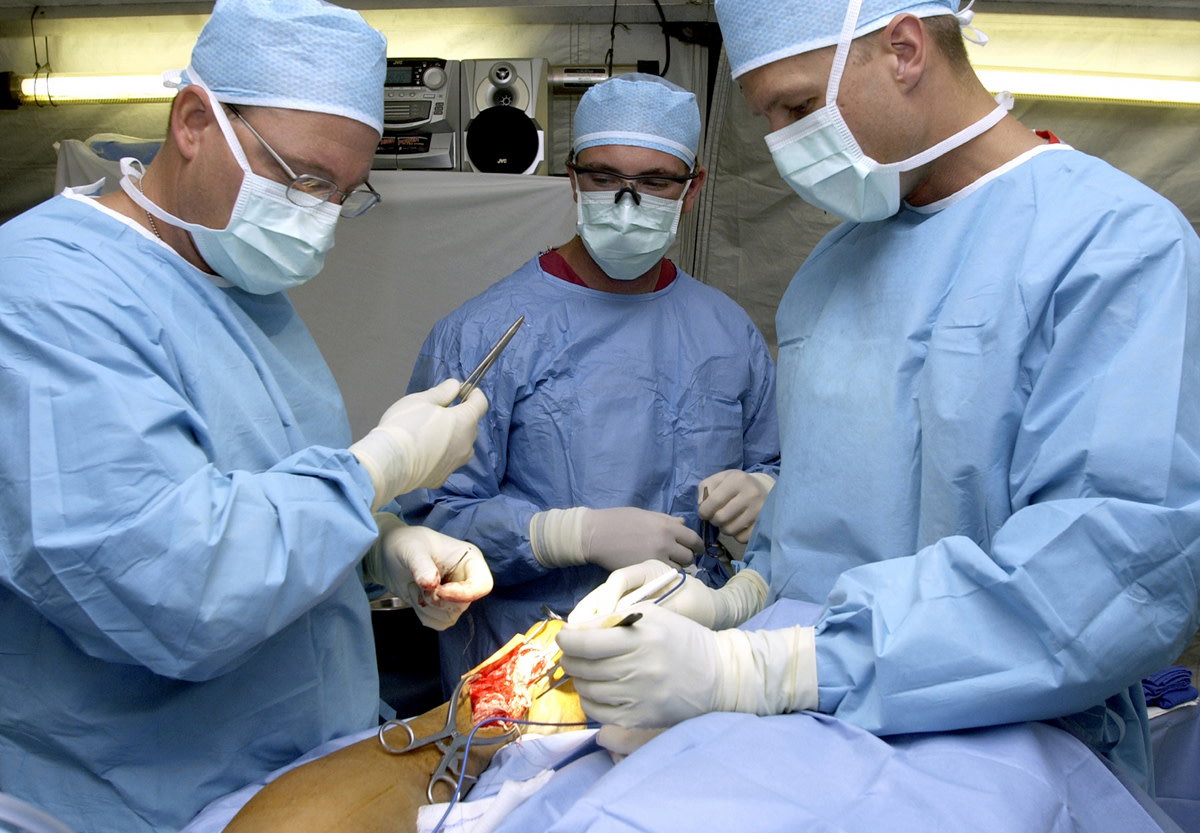 U.S. Air Force surgeons Dr. Patrick Miller (left), Dr. Michael Hughes (right), and surgical technician SrA Ray Wilson from the 379th Expeditionary Medical Squadron, repair the ruptured achilles tendon of a servicemember on March 11, 2003.