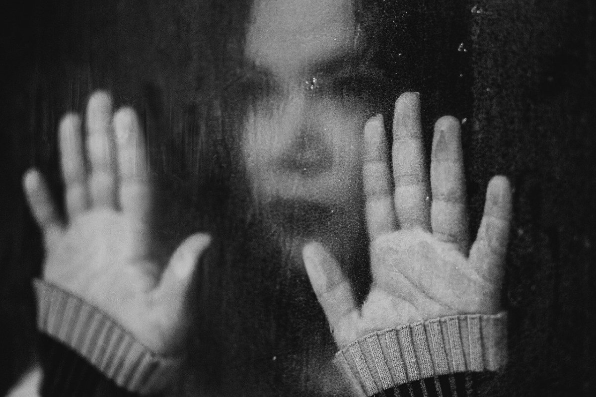 Girl looking through rain-streaked window.