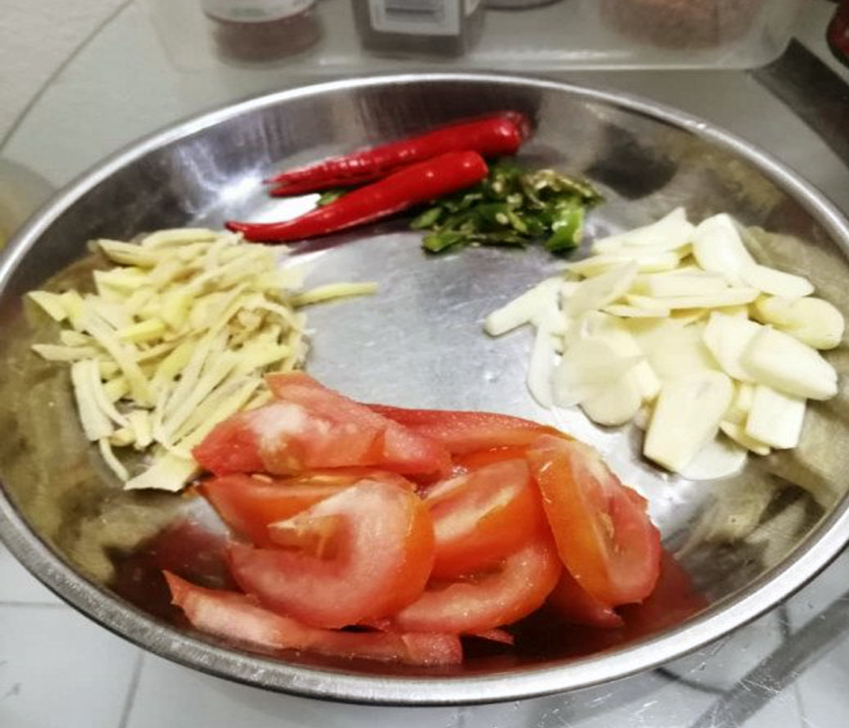 Clockwise from top - Red and green chilies, sliced garlic, sliced tomatoes, and julienned ginger