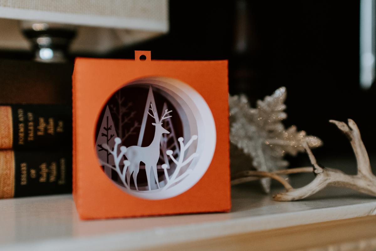 Reindeer and pine trees cutouts enclosed in a viewing box.