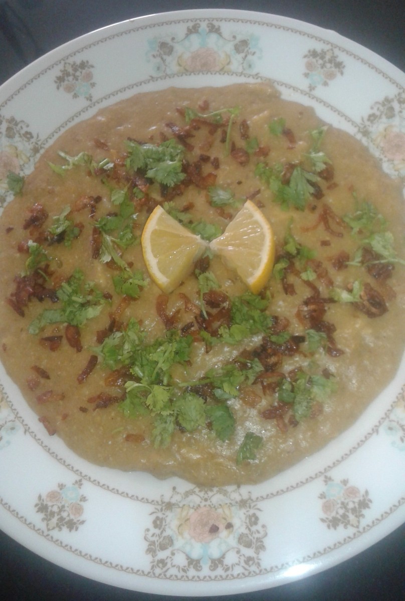 Delicious chicken haleem (stew) garnished with fried onion, coriander leaves and lemon.
