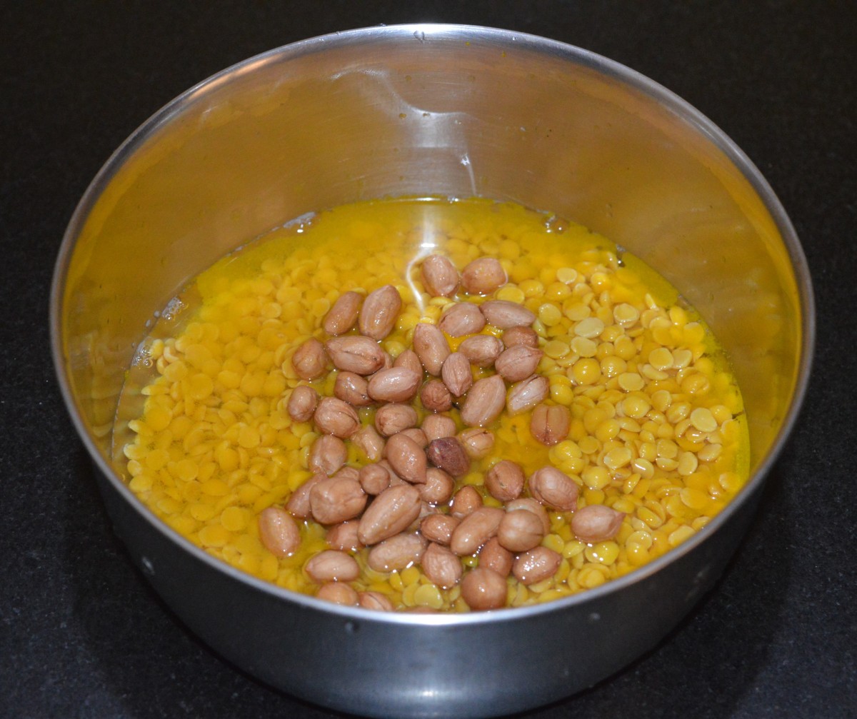 Step one: Wash split pigeon pea. Add it to a cooker container. Add 2 cups water, a teaspoon of oil, washed peanuts, and turmeric powder.