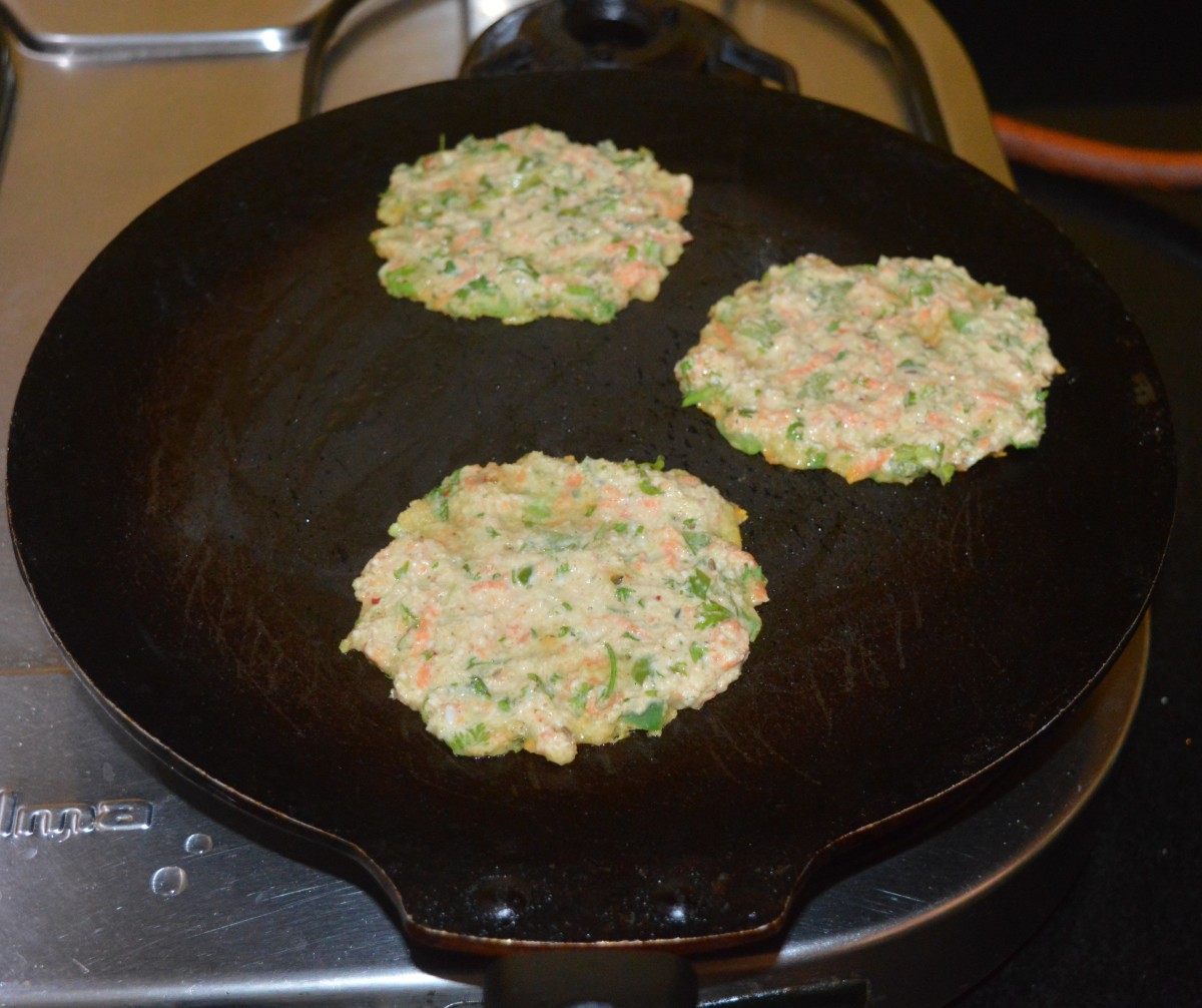 Step three: Heat a pan or griddle. Grease it with oil. Make 3 or 4 small pancakes (cheela) on it. Spread each of them a little. Keep the pan at medium-high heat.