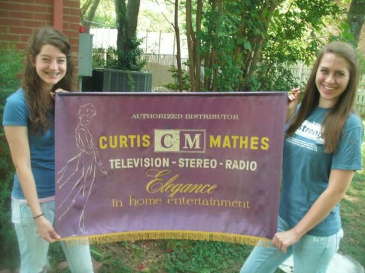 Karah Waters and Cora Waters are holding up a Curtis Mathes Banner made in 1959 for a Showroom of the first High Fidelity stereos made in Texas.  The first authorized dealership in true high fidelity console stereo systems.  