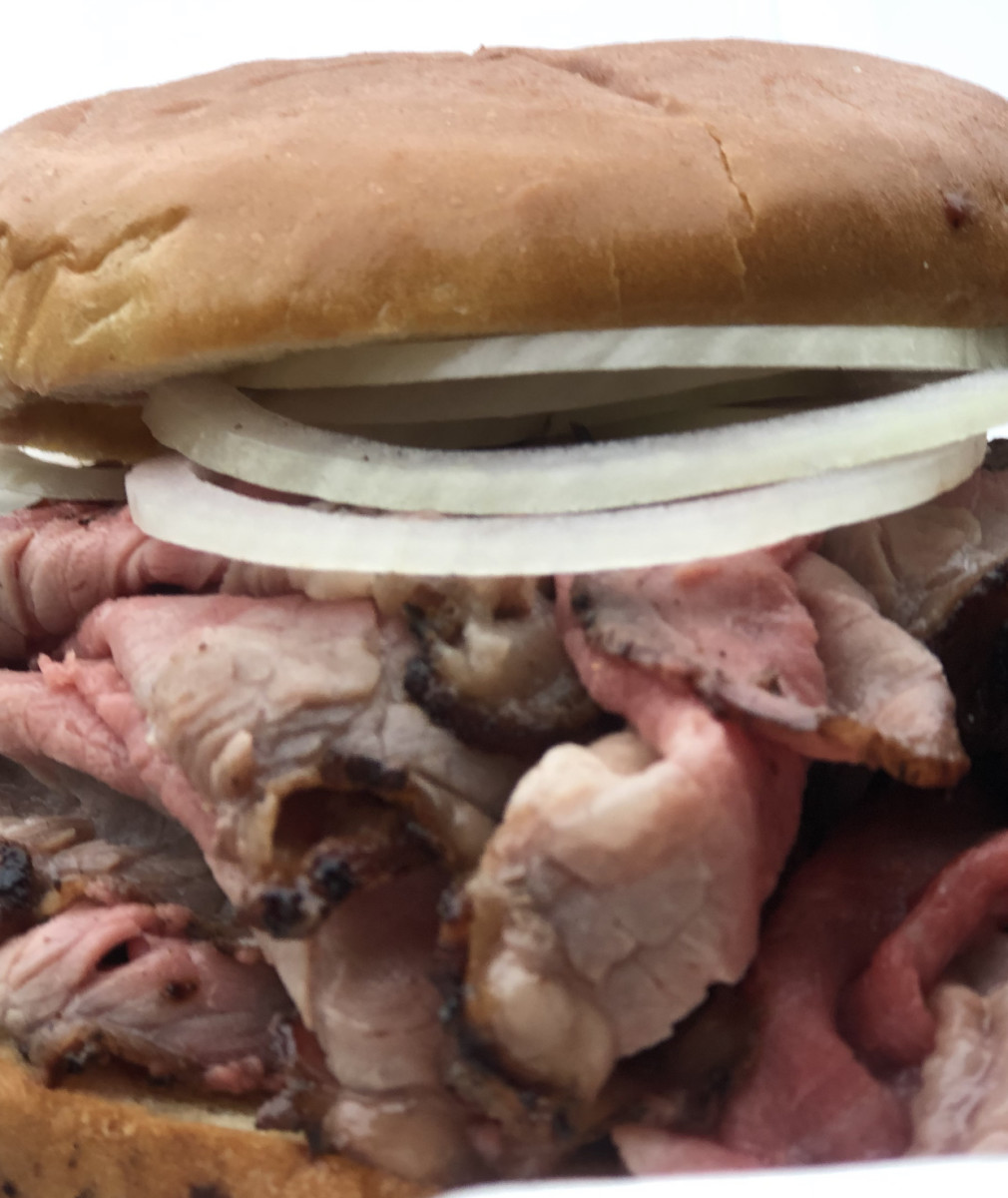 The pit beef sandwich is served medium rare, sliced thin, and piled high on a round bun, often garnished with raw onions.  Used with permission by Owner Wayne Schafer.