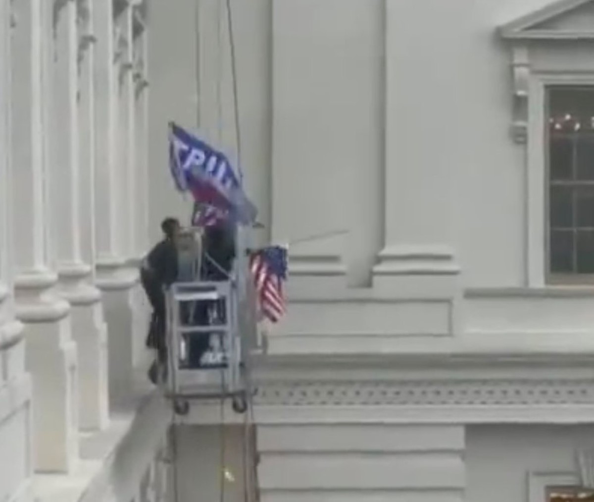 Insurgents remove the American Flag to fly a Trump flag. 