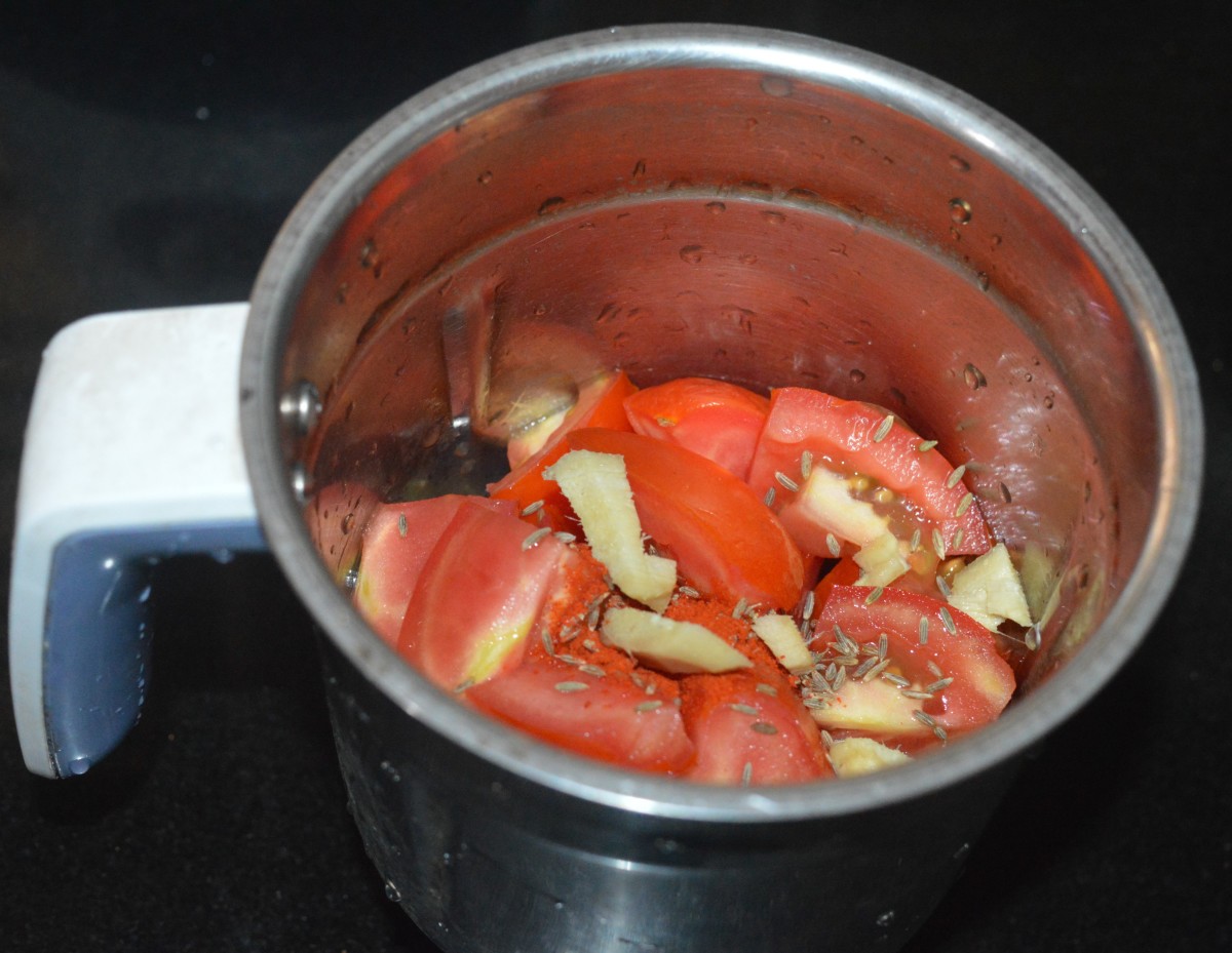 Step one: In a mixer jar, add chopped tomatoes, ginger, red chili powder, and cumin seeds. 