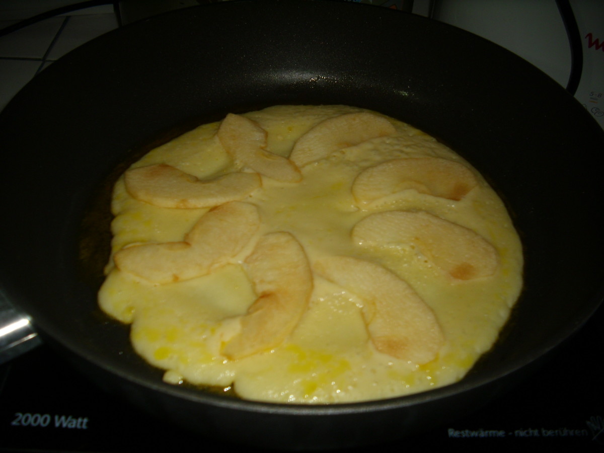 Fried German pancake with apple slices.
