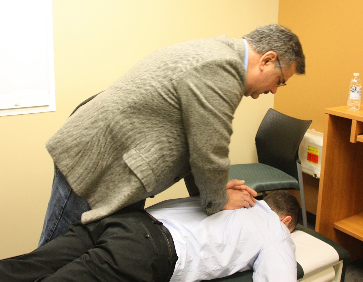 A chiropractor performs a spinal adjustment on his patient. 