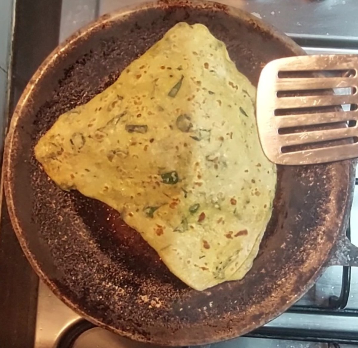 Heat a frying pan over medium flame and add a few drops of ghee. Dust off excess flour from the first thepla and fry it. Drizzle a few drops of ghee over the thepla, flip and cook on both sides till brown spots appear. Transfer to a plate.