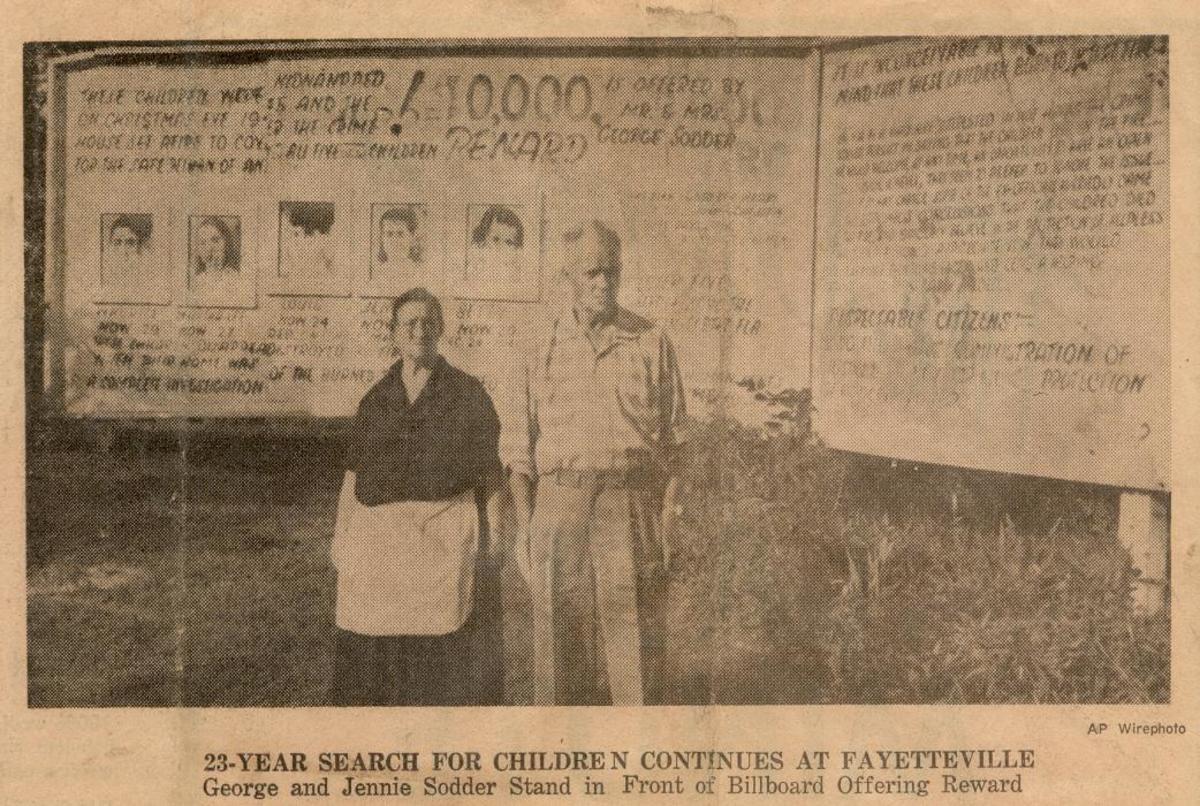 Jennie and George Sodder standing in front of the billboard