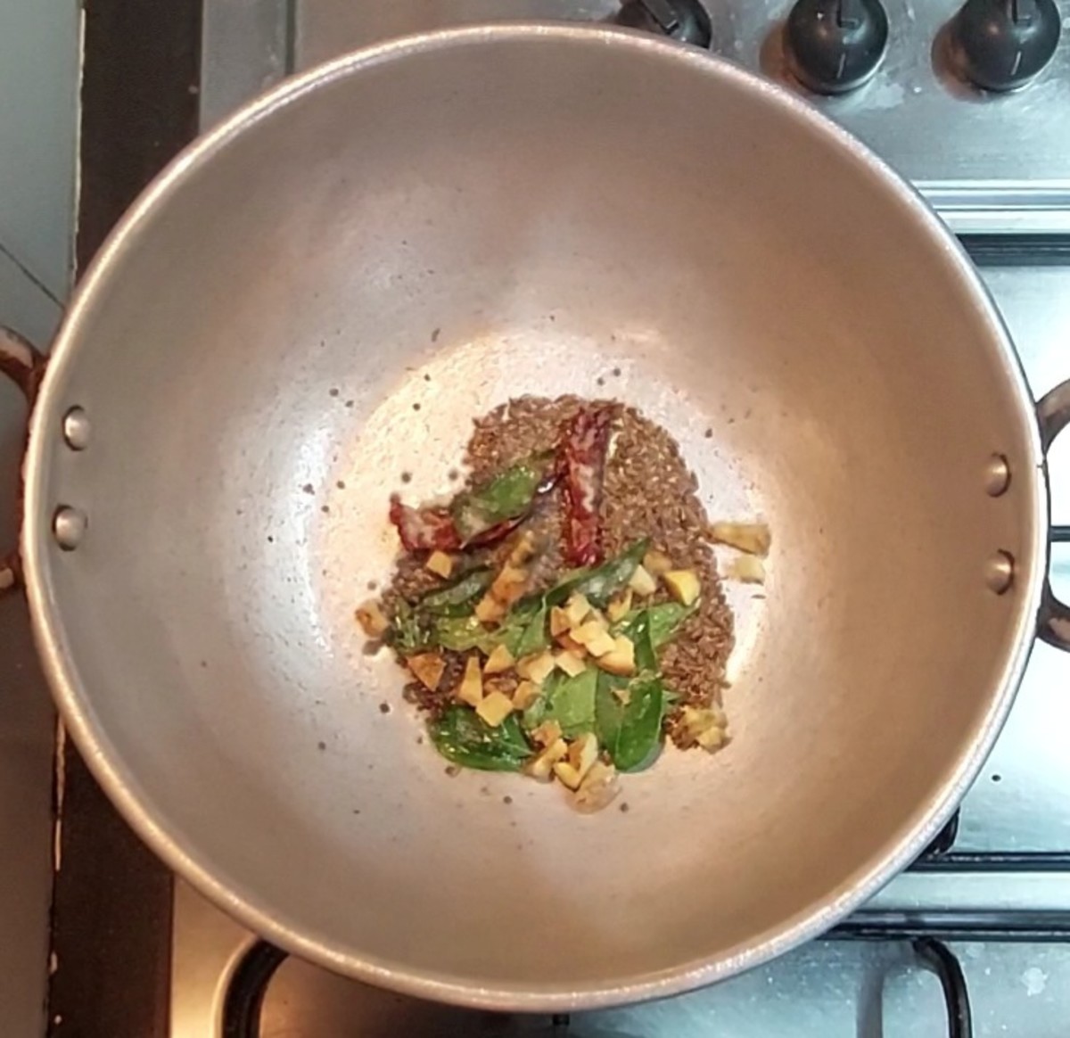 In a pan, heat 1 teaspoon oil, splutter 1/2 teaspoon mustard seeds, 1 teaspoon cumin seeds, add 1-2 red chilies, a spring of curry leaves, 1/4 teaspoon hing, 1 teaspoon chopped ginger, fry for a minute.