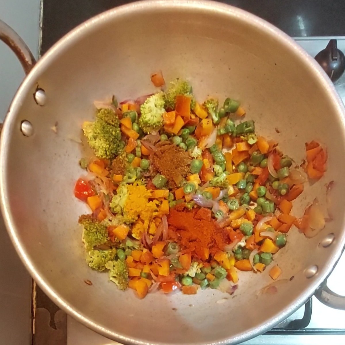 Add 1/2 teaspoon turmeric  powder, 1 teaspoon red chili powder, 1/2 teaspoon pav bhaji masala, mix and combine well with the vegetables.