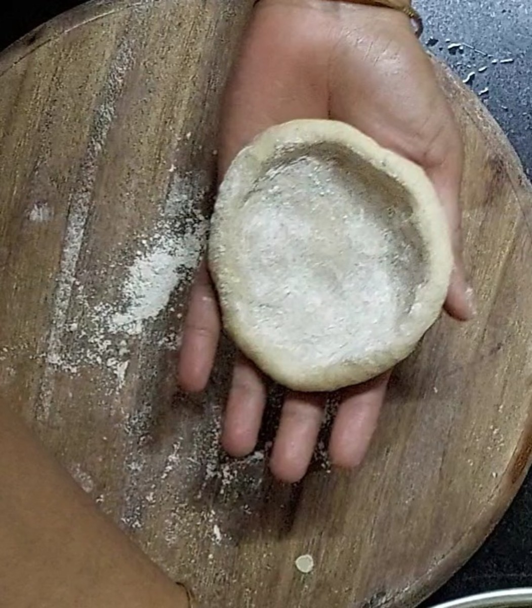 Make medium sized roundels from the dough and peas mixture. Take a dough roundel in the rolling board, sprinkle wheat flour, make cup like structure.