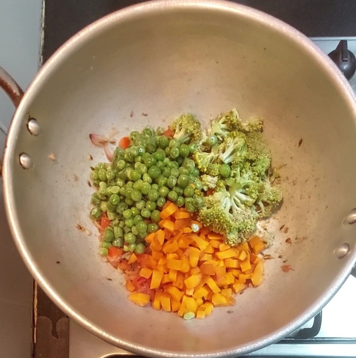 Add 1/4 cup chopped french beans, 1/2 cup carrots, 7-8 florets broccoli (soaked in hot water for 10 minutes), 1/4 cup frozen peas, fry for a minute. Add salt to taste.