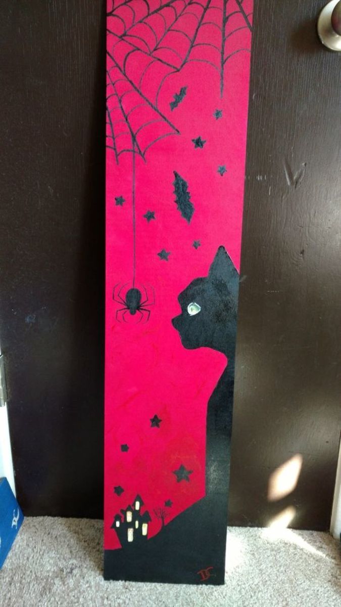 Paint an old board with a black cat and spiders