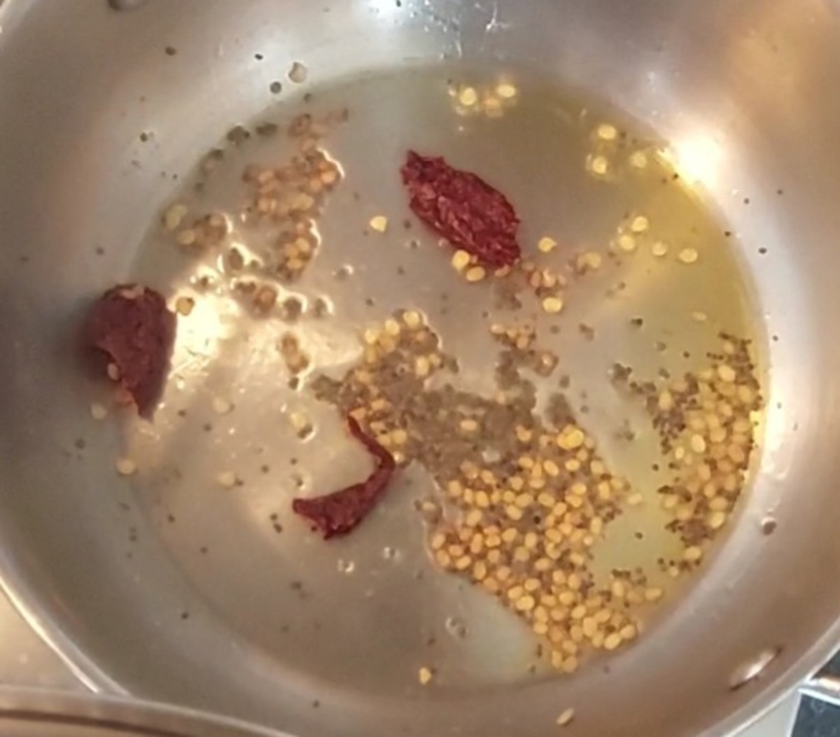 In a frying pan, heat 1 teaspoon ghee and splutter 1/2 teaspoon mustard seeds. Add 1/2 teaspoon urad dal and saute till golden brown. Add 1-2 broken red chilies and 1/4 teaspoon hing. Switch off the flame