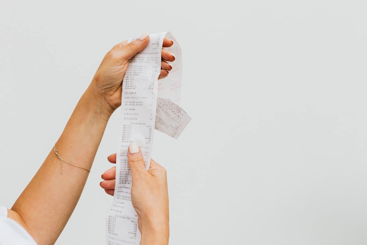 A person holding a long receipts 