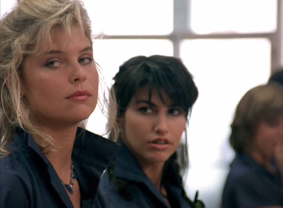 After listening to a snide comment, Benny (Kate Vernon) hurls an insult back, as her friend (Gina Gershon) looks on stunned