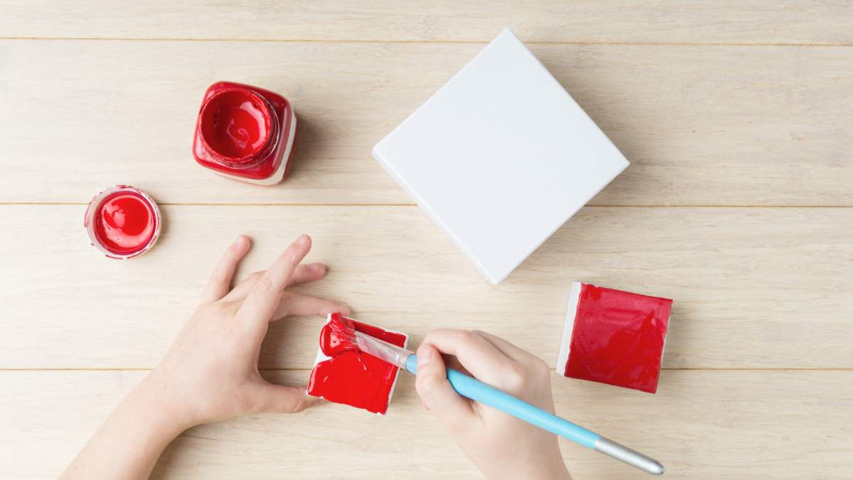 Hands painting the top of a small box red