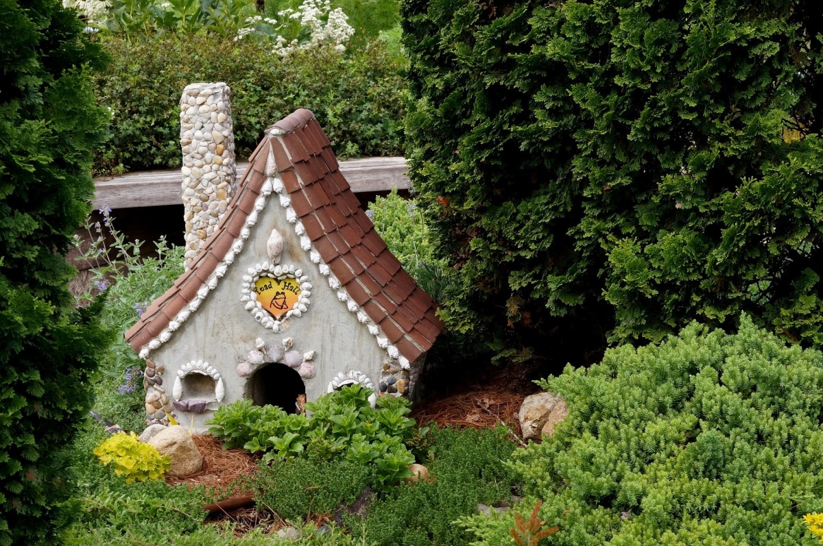 A-frame clay fairy house with chimney in a garden