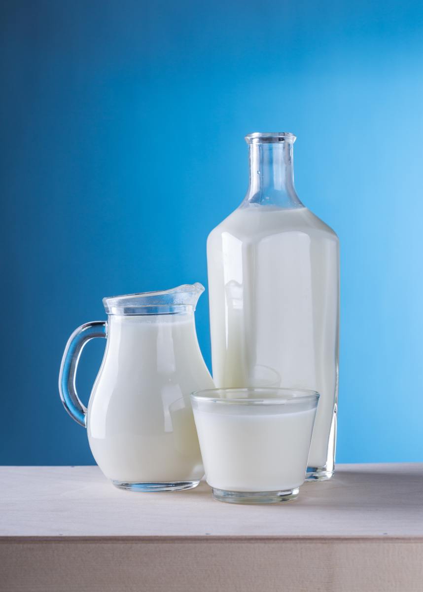cup of milk, jar of milk and bottle of milk against a blue background 